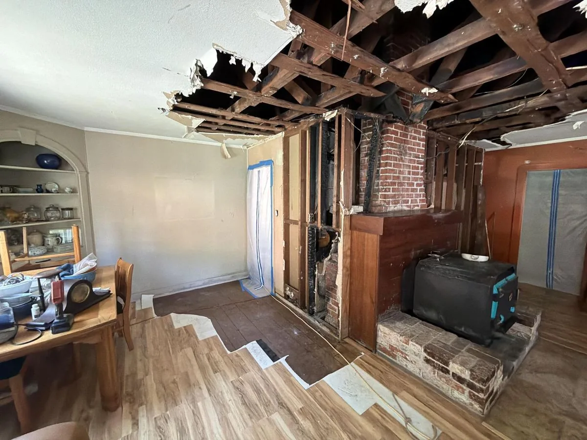 Fire damage cleanup in progress after a chimney fire — charred framing exposed, containment in place, by North Coast Restoration