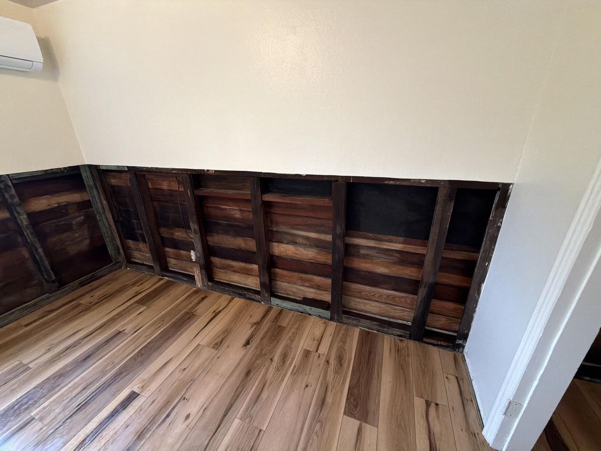 Wall cavity cleaned, treated, and dried after mold remediation, with new flooring installed