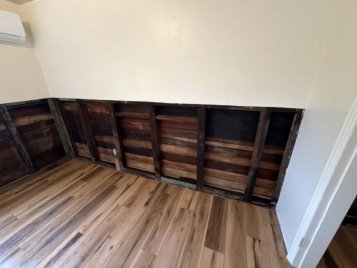 Wall cavity cleaned, treated, and dried after mold remediation, with new flooring installed
